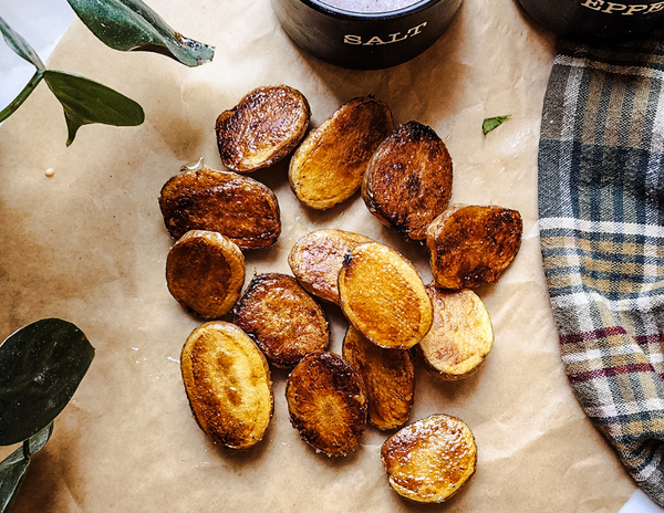roasted baby potatoes laying on parchment paper on the counter in the sun