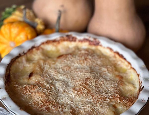 white pie dish filled with chicken cordon bleu. Tan and orange squash fills the backdrop.