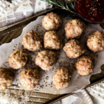 White textured background, gold tray with parchment paper, 12 meatballs on top.