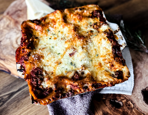 An overhead shot of lasagna in a square pan topped with golden-brown, bubbly cheese topping.