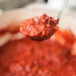 A close up of homemade spaghetti sauce with tomato sauce, ground beef and herbs.