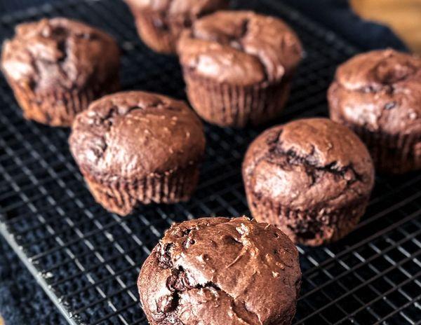 A close-up of double chocolate banana muffins topped with chocolate chips, a chocolate batter and bananas.