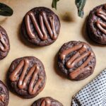 Parchment paper with 6-7 homemade fudge rounds sitting on top with a black and white checkered tea towel near by on the side