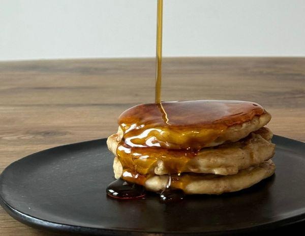 A stack of fluffy Greek yogurt pancakes topped with fresh berries and a drizzle of maple syrup.