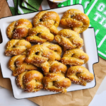 soft pretzels sitting on a white plate in arranged rows near some game time napkins