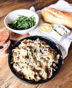 A creamy slow cooker ground beef stroganoff served over egg noodles, topped with onions and mushrooms.