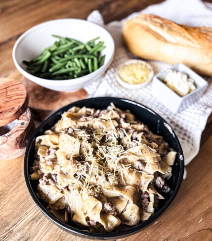 A creamy slow cooker ground beef stroganoff served over egg noodles, topped with onions and mushrooms.