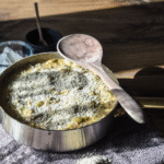 Easy one pan chicken, broccoli and cheese gnocchi in a stainless steel skillet with a gold handle on a wooden background with a wooden spoon across the top.