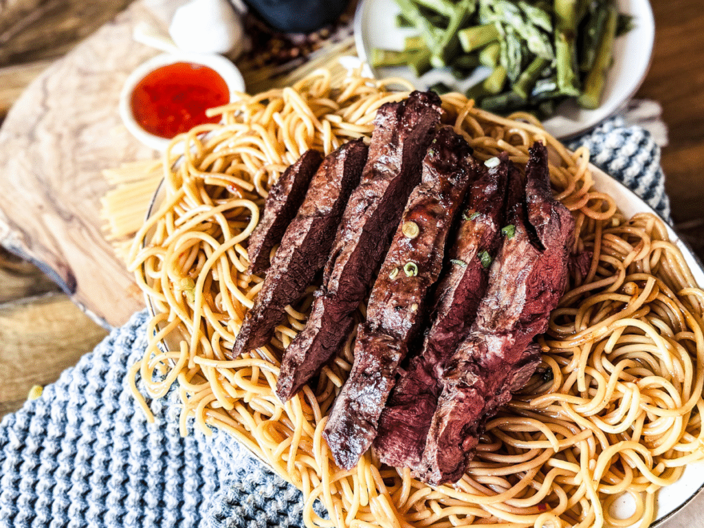Asian Style Flank Steak on a bed of spicy noodles.