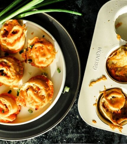 Boursin Tortilla Breakfast Rolls on a plate with a muffin tin to the right. Green onions sit to the top left.
