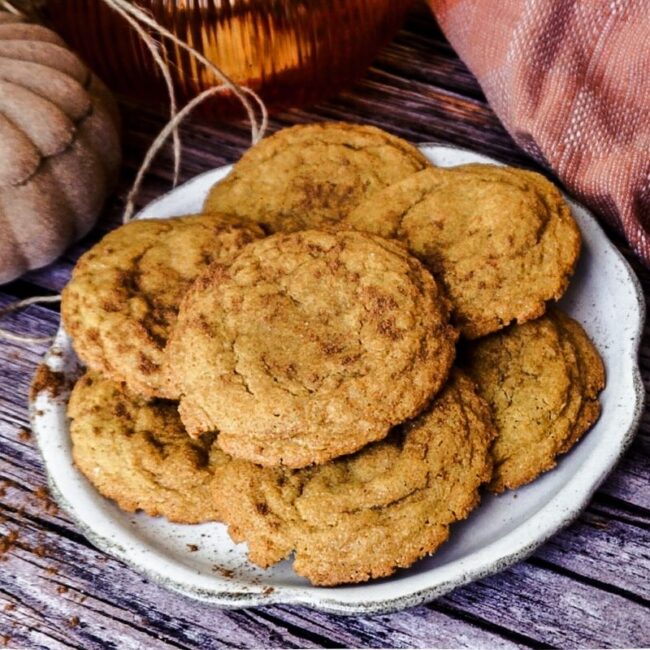 Pumpkin Snickeroodle Cookies stacked on a plate with a wooden backdrop. A