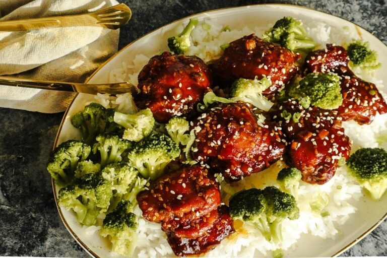 Sweet and Spicy Teriyaki Chicken on a bed of rice with broccoli and sesame seeds sprinkled on top. Gold tongs rest to the left.