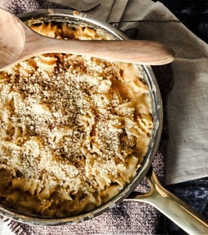 Baked Macaroni and Cheese with Bread Crumbs on Top in a skillet. A black back drop with off white tea towels