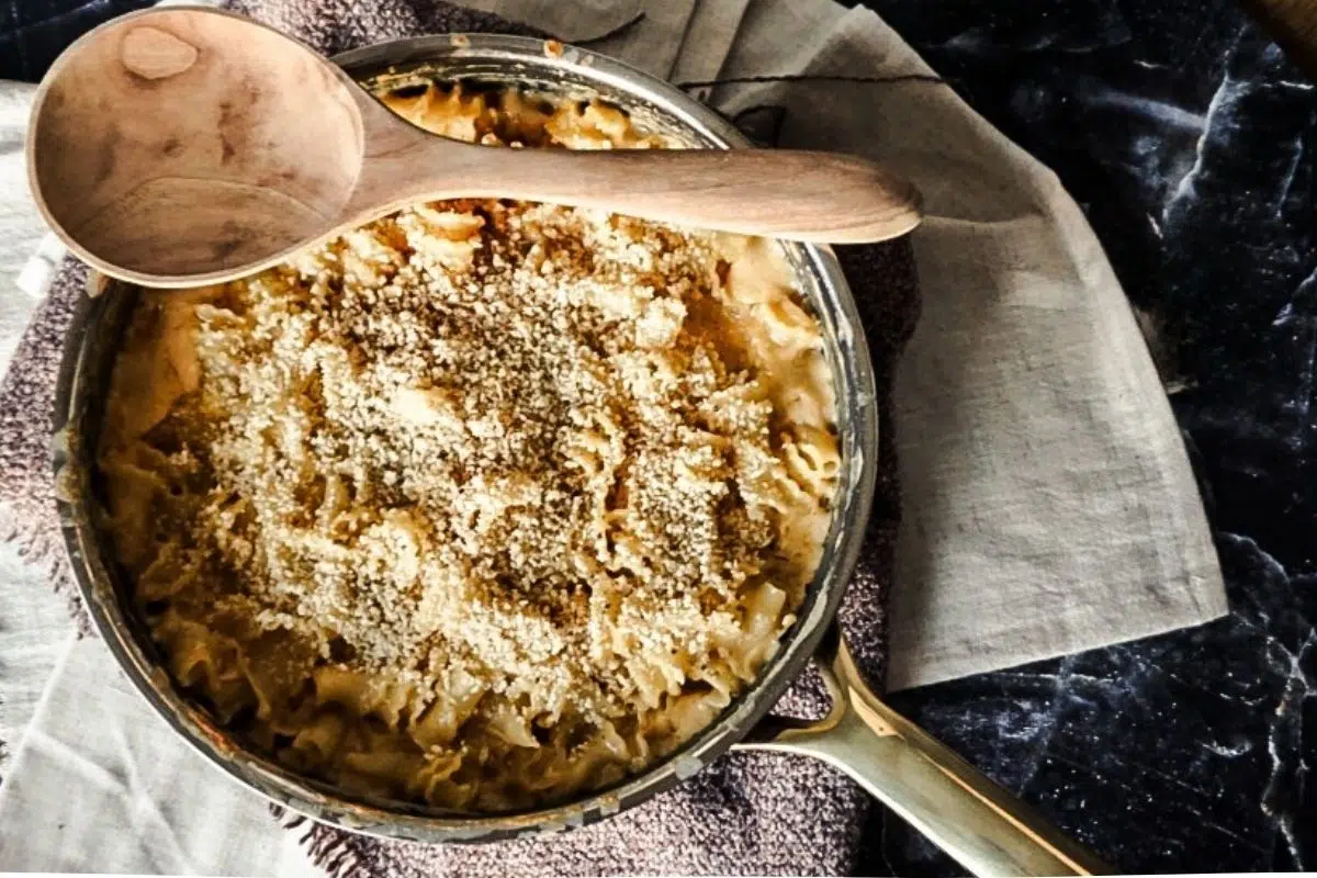 Baked Macaroni and Cheese with Bread Crumbs on Top in a skillet. A black back drop with off white tea towels