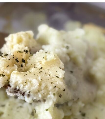 A scoop of chicken and mashed potato bake with a wooden spoon over the casserole.