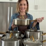 Anna with 5 GreenPan laid out in front of her, holding one. 